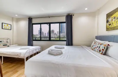 a bedroom with two beds and a window at Bangkok Watergate Townhouse \u66fc\u8c37\u4e2d\u5fc3\u6c34\u9580\u5bb6 in Bangkok