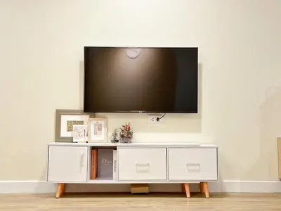 a white entertainment center with a flat screen tv on a wall at Happiness Sleep in Thung Si Kan