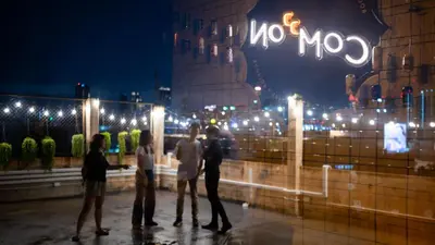 a group of people standing in front of a nomo sign at night at C'HOUSE Bangkok in Pom Prap